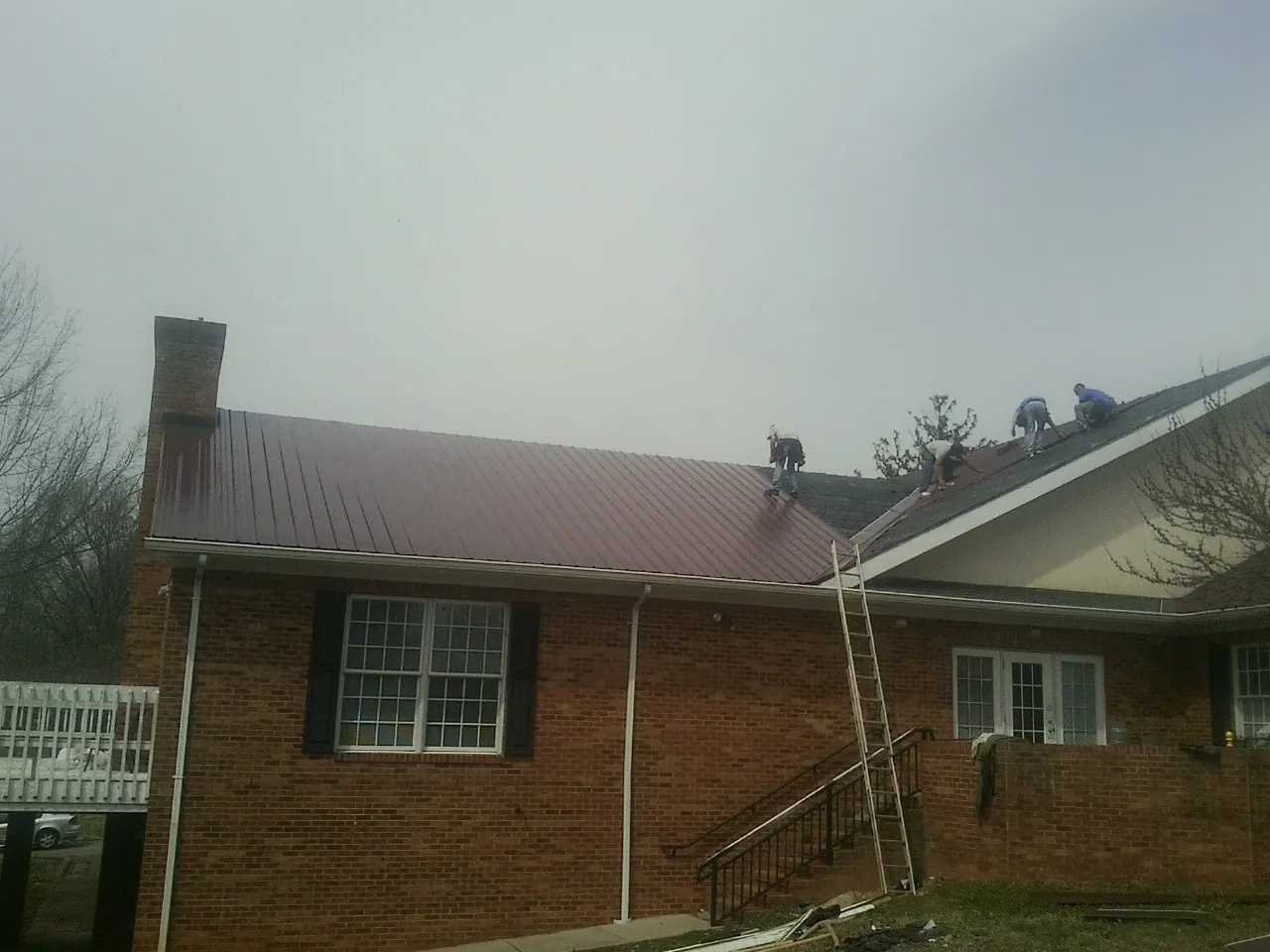 Crew setting red metal roofing panels on a brick home in Atlantic City