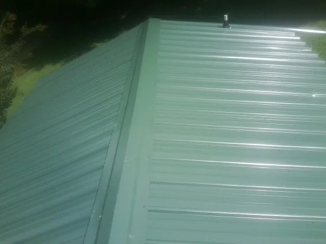 New green metal panels meeting at the ridge of a roof — Flat Roof Repair work by our crew in Atlantic City
