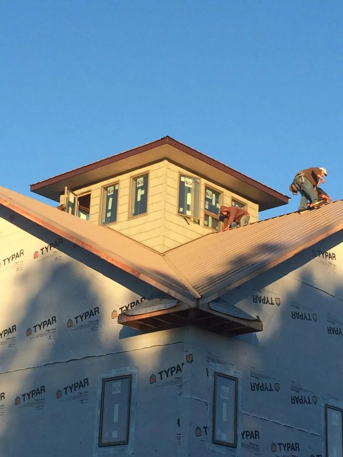Roofers working around a rooftop cupola on a new metal roof at sunset — Roof Waterproofing in Atlantic City by Roofing Brothers